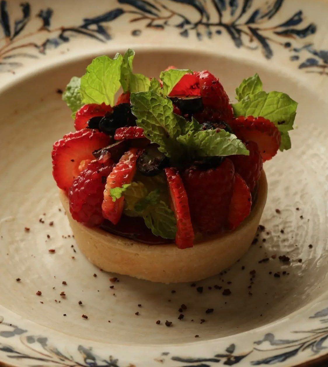 A strawberry tart on a hand-painted plate