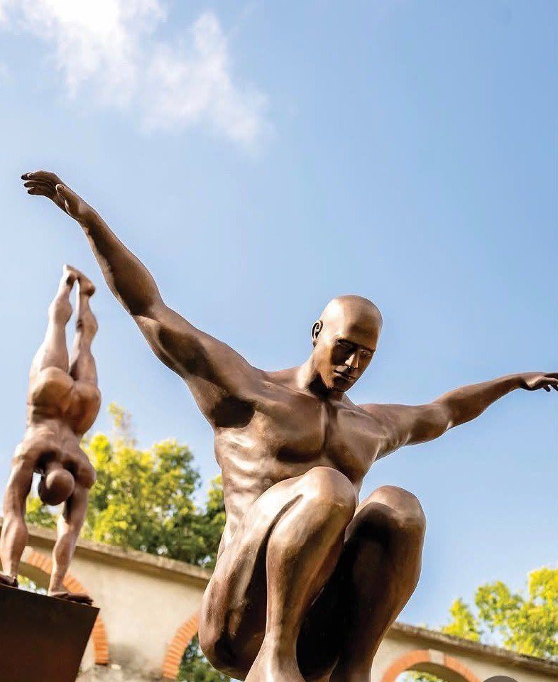Bronze sculptures of divers against a blue sky